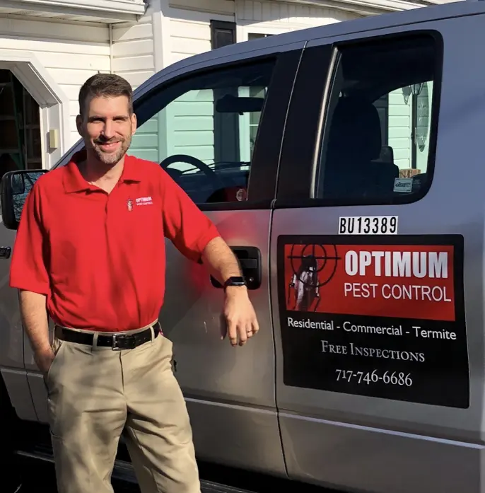 Owner of Optimum Pest Control standing beside service truck